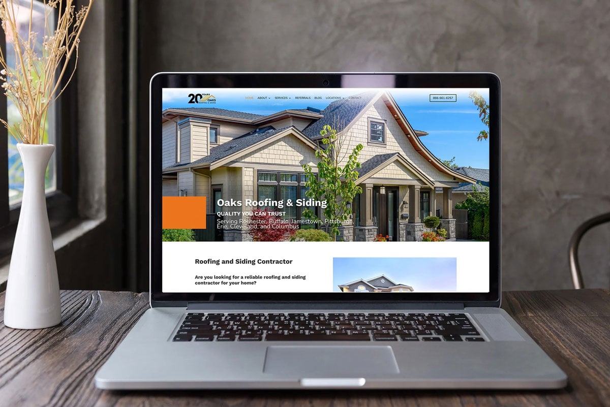 Laptop displaying a website about house construction. The website features a large house image.